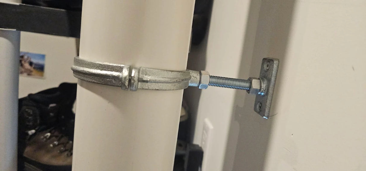 Split ring hanger kit installed on a 4-inch PVC radon vent pipe, mounted to wall via threaded rod and plate