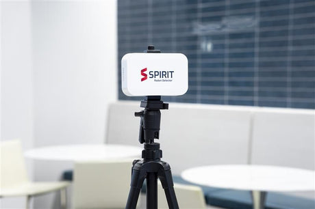 Radonova SPIRIT radon monitor mounted on a camera tripod in a meeting room