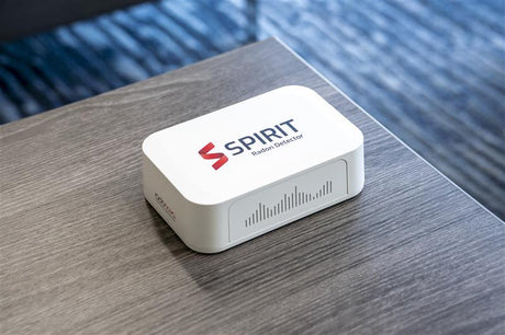 Radonova SPIRIT radon monitor sitting on a wooden desk in an office