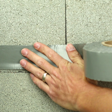 StegoTack tape being rolled into place — Canadian radon mitigation crawlspace barrier installation