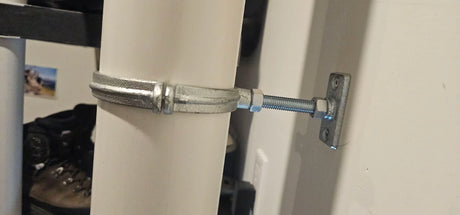 Split ring hanger kit installed on a 4-inch PVC radon vent pipe, mounted to wall via threaded rod and plate